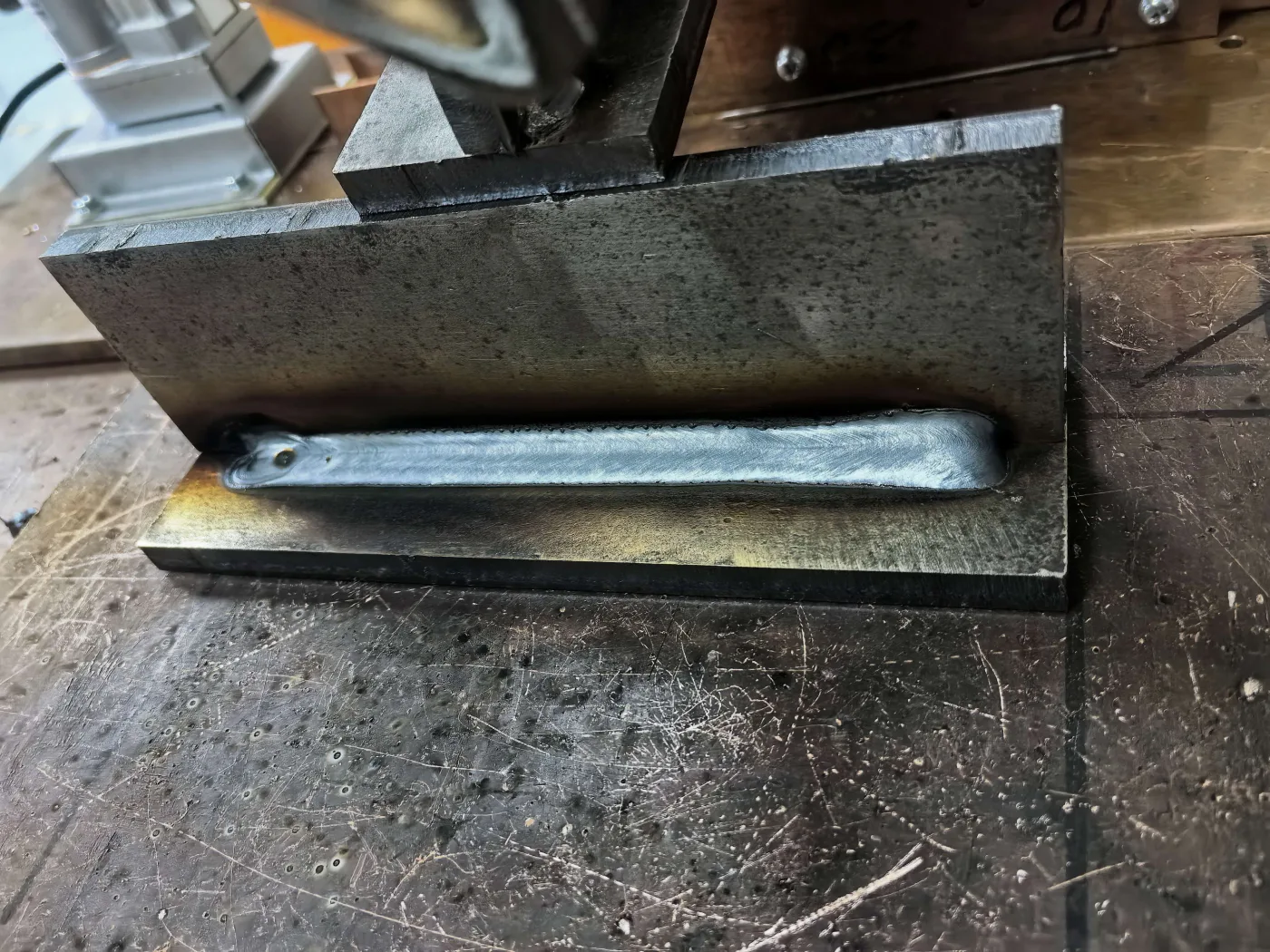 Finished spatter-free fillet weld bead with uniform ripple pattern and clean surrounding plate