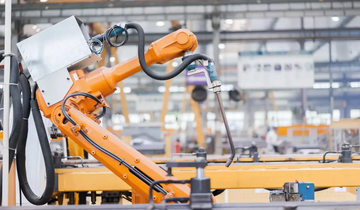 Industrial robotic welding arm with welding torch mounted on a positioner in a fabrication shop